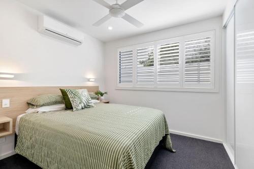 a bedroom with a bed and a window at Rooftop Alexandra Headland in Alexandra Headland