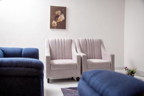 a living room with two chairs and a picture on the wall at Modern Village Apartments in Chipata