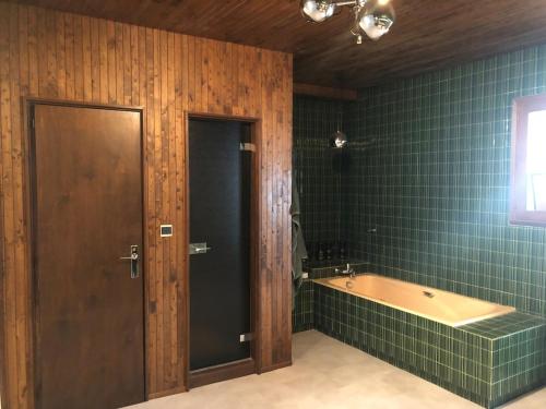 La salle de bains est pourvue d'une baignoire et de carrelage vert. dans l'établissement Appartement 220m2 15P avec Sauna, hyper center Luchon, à Luchon
