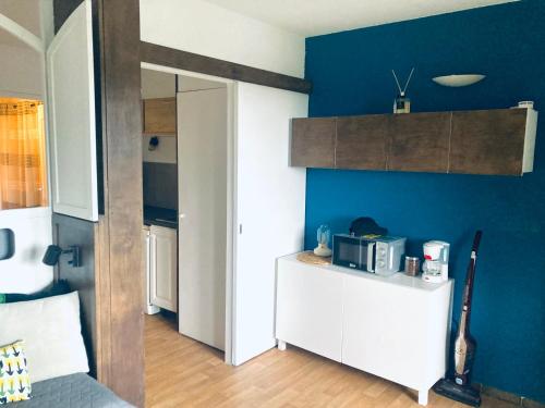 kuchnia z kuchenką mikrofalową i niebieską ścianą w obiekcie Hyeres port bel appartement w Hyères