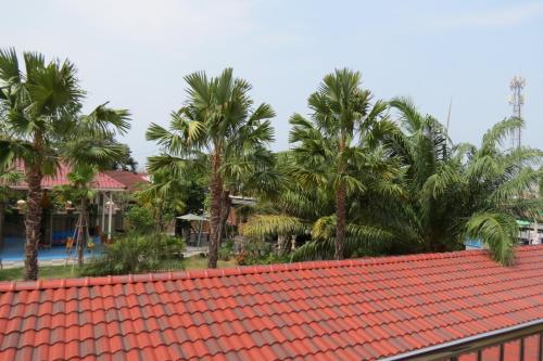 an orange roof with palm trees in the background at Baan Bee Residence in Nong Prue