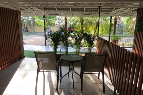 a table and chairs on a screened porch with trees at Baan Bee Residence in Nong Prue