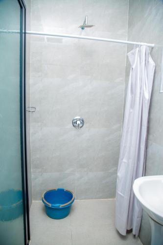 a shower with a blue bucket in a bathroom at Modern Village Apartments in Chipata