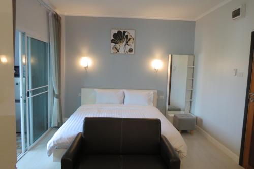 a bedroom with a large bed and a couch at Baan Bee Residence in Nong Prue