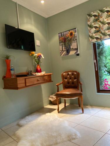 a living room with a chair and a television at Bollinger Guest House in George