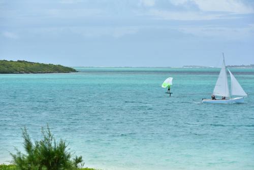 a sail boat in the water next to a beach at Paradise Beach Luxury Beachfront Apartment Pointe d'Esny in Pointe d'Esny
