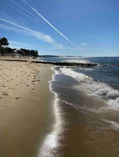 a beach with footprints in the sand and the water at Maison Eysines- A10 in Eysines