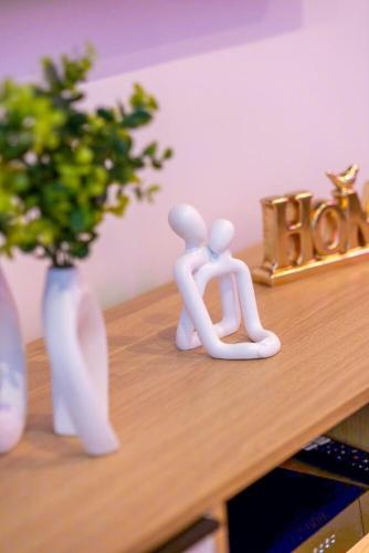 two white sculptures sitting on a wooden table with a vase at Balneotherapy, cozy, family-friendly in Villars