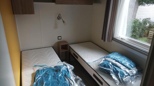 une petite chambre avec deux lits et une fenêtre dans l'établissement MH 385 3 chambre ET 1 salle de bain 40M2 dans camping 4 étoiles, à Saint-Julien-en-Born