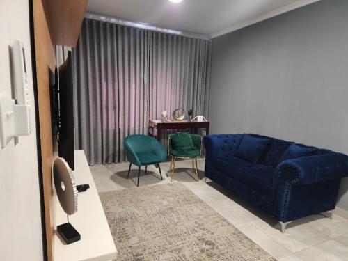 a living room with a blue couch and a table at Sarona city Habitat Alpha apartments C202 Gaborone in Gaborone