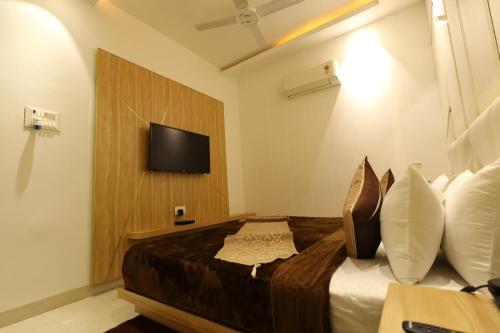 a bedroom with a bed with a tv on the wall at Hotel Darbar-E-Khas in Bareilly