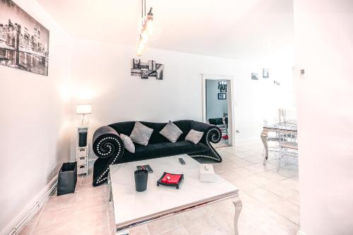 a living room with a black couch and a table at Chez Louis le Tonnelier, Sauna et espace détente privés in Le Mesnil-sur-Oger