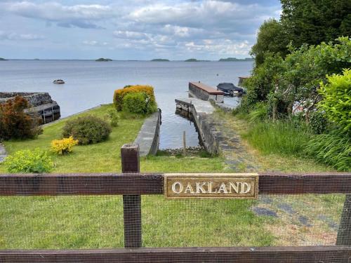 un panneau indiquant un oakland sur une clôture près d'une masse d'eau dans l'établissement Lakeside Apartment Retreat in Oughterard Connemara, à Oughterard