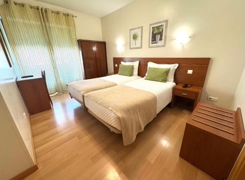 a hotel room with two beds with green pillows at Paradouro in Lisbon