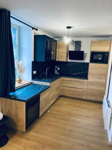 une cuisine avec un comptoir bleu et des placards en bois dans l'établissement Le Pattulacci, à Rocroi