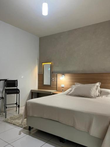 ein Schlafzimmer mit einem Bett, einem Spiegel und einem Stuhl in der Unterkunft Hotel Samambaia in Indiara 