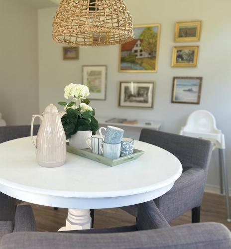 a white table with a vase and flowers on it at Centralt och mysigt boende i Tomelilla in Tomelilla