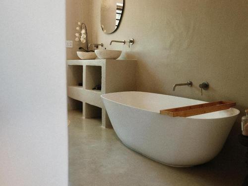 a white bath tub in a bathroom with two sinks at Kokon Boutique Guesthouse in Somerset West