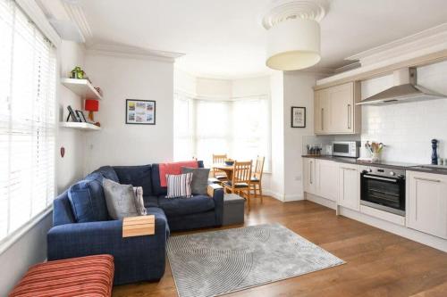 a living room with a blue couch and a kitchen at Modern Southville Apartment 5 Min Walk to Centre in Bristol