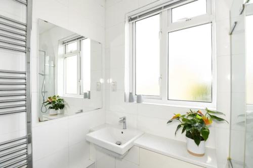 a white bathroom with a sink and a window at Modern Southville Apartment 5 Min Walk to Centre in Bristol