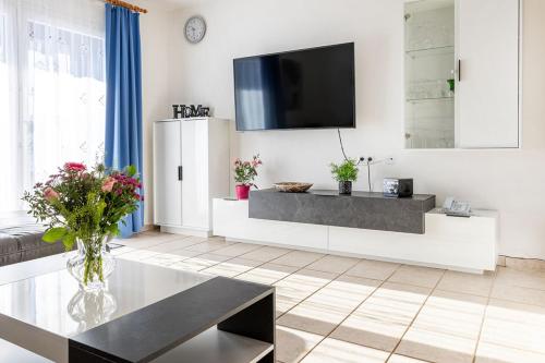 un salon avec une télévision sur un mur dans l'établissement Ferienhaus Nr 105, Kategorie Komfort, Feriendorf Hochbergle, Allgäu, à Karlsebene