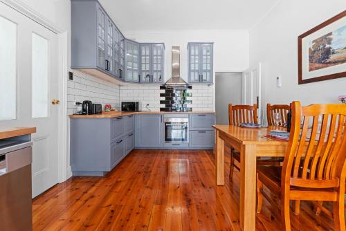 a kitchen with blue cabinets and a wooden table at Character 1880s Renovated Cottage - Quiet location in Adelaide