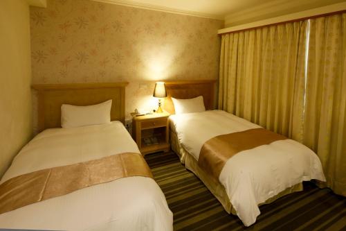 a hotel room with two beds and a window at Cambridge Tainan Hotel in Tainan