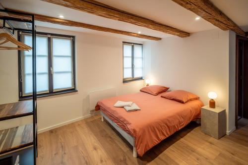 a bedroom with a bed with orange sheets and windows at Maison alsacienne in Sélestat