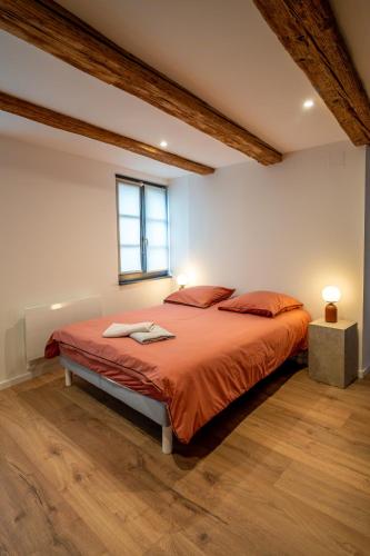 une chambre avec un lit avec des draps orange et une fenêtre dans l'établissement Maison alsacienne, à Sélestat