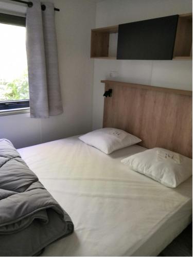 un lit avec deux oreillers dessus dans une chambre dans l'établissement Mobilhome de charme au bord du Lac, à Biscarrosse