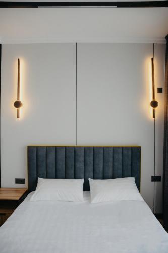 a bedroom with a large white bed with two lamps at Апарт-отель Tong Marina in Tong
