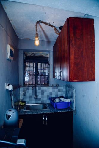 a kitchen with wooden cabinets and a sink and a window at Cozy Studio Apartment Makindye in Kampala