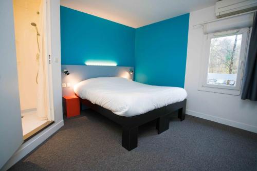 - une chambre avec un mur bleu et un lit dans l'établissement Fasthotel Artigues, à Artigues-près-Bordeaux