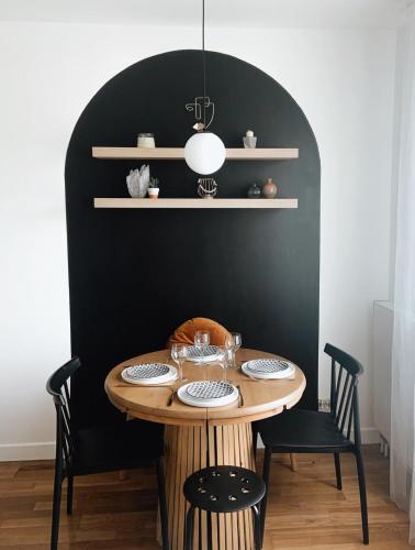 une table à manger avec des chaises et un mur noir dans l'établissement Appartement avec une place de parking, à Hendaye