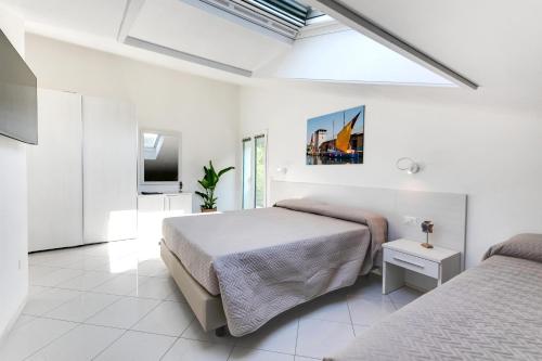 a white bedroom with two beds and a tv at Residenza Acquamarina - Siroli Collection in Cervia