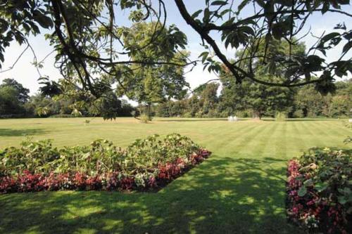 a park with a large field of grass with flowers at Grovefield House Hotel in Slough