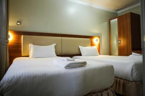 a hotel room with two beds with white sheets at ENN Business Hotel in Kajansi