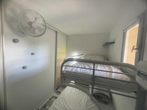 a room with a bunk bed and a fan at Appartement avec vue sur la mer in Six-Fours-les-Plages