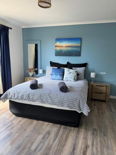 a bedroom with a large bed with blue walls at Views of the Tamar River in Clarence Point