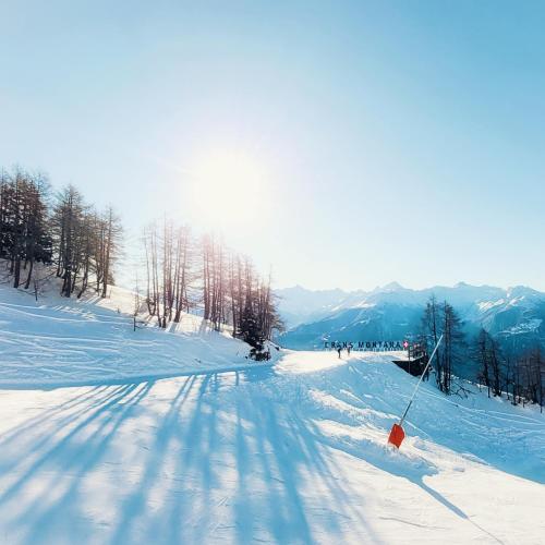 a group of people skiing down a snow covered slope at L'AvantGardiste, Spacious 6 bedrooms duplex, panoramic view in Crans-Montana