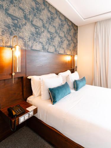 a hotel room with a large bed with blue pillows at Fourteen Hotel Ain Sebaa in Casablanca