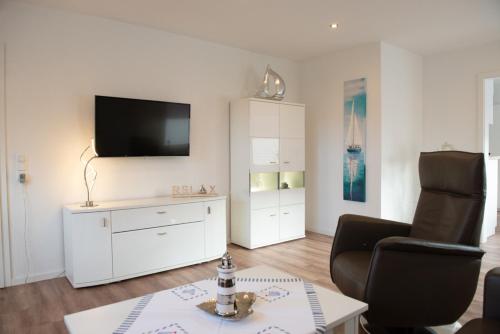 a living room with a chair and a tv on a wall at Deichhaus vorne in Norden