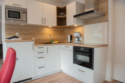 a kitchen with white cabinets and a stove top oven at Deichhaus vorne in Norden