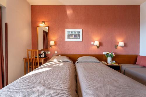 two beds in a room with a couch and a mirror at Queen Olga Hotel in Thessaloniki