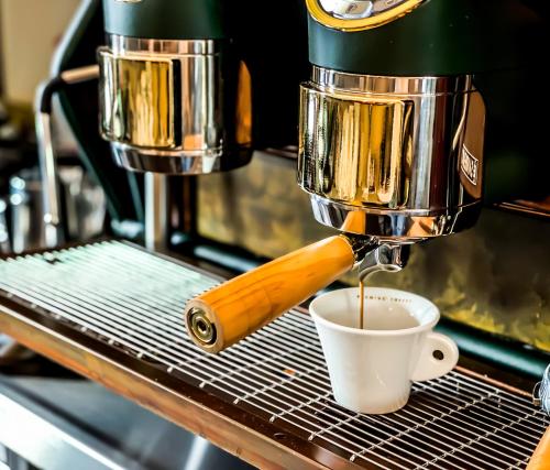 a coffee maker making a cup of coffee on a rack at Trompeterschlössle Hotel & Residence in Tägerwilen