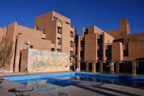a swimming pool in front of a building with a map at Hôtel Rose Mgouna in Kalaat MGouna