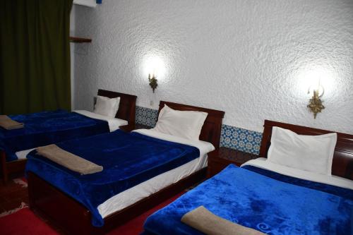 a room with three beds with blue sheets at Hôtel Rose Mgouna in Kalaat MGouna