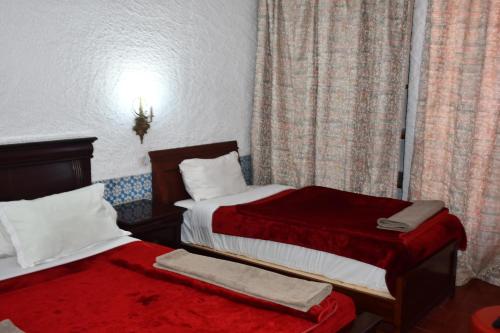 a hotel room with two beds and a window at Hôtel Rose Mgouna in Kalaat MGouna