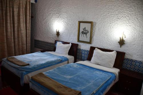two beds in a hotel room with blue sheets at Hôtel Rose Mgouna in Kalaat MGouna