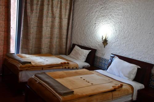 two twin beds in a room with a window at Hôtel Rose Mgouna in Kalaat MGouna